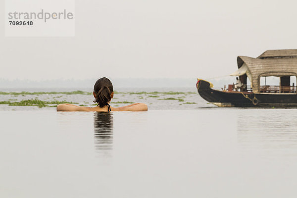 Indien  Kerala  Junge Frau im Schwimmbad mit Blick auf Hausboot