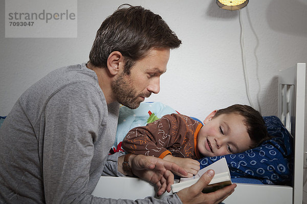 Germany  Berlin  Father reading book while son sleeping