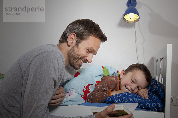 Deutschland  Berlin  Vater liest Buch im Schlaf des Sohnes