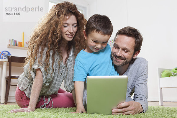Germany  Berlin  Family using digital tablet on floor