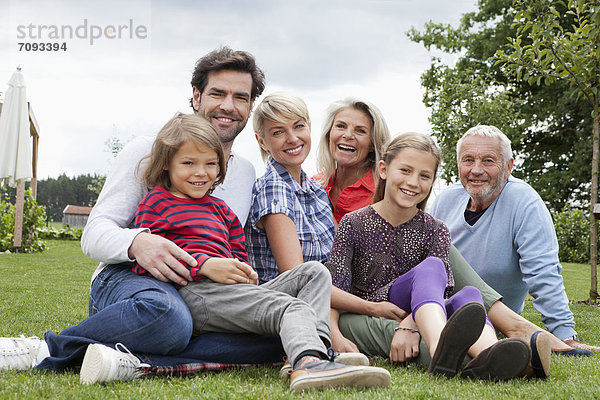 Germany  Bavaria  Nuremberg  Family sitting in grass  smiling  portrait