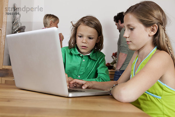 Mädchen und Junge mit Laptop in der Küche