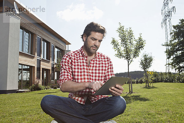 Erwachsener Mann mit digitalem Tablett im Garten