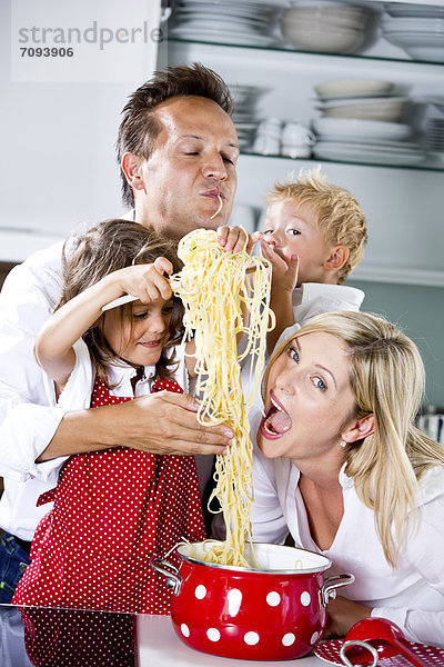 Germany  Family playing with spaghetti on kitchen worktop