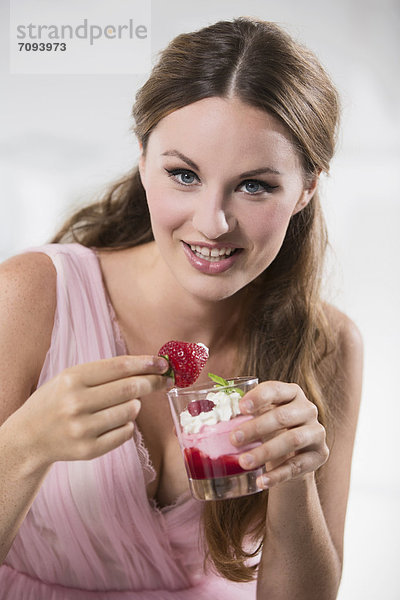 Germany  Young woman holding dipped strawberry in her hand  smiling  portrait