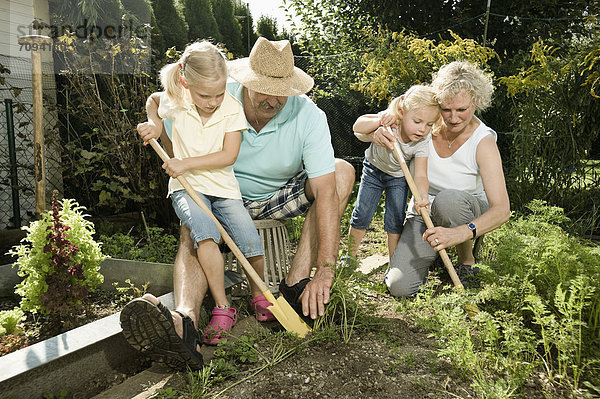Germany  Bavaria  Grandparents with children working in vegetable garden