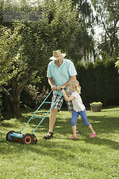 Germany  Bavaria  Grandfather with children mowing lawn
