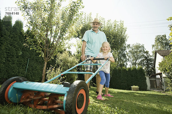 Deutschland  Bayern  Großvater mit Kindern beim Rasenmähen