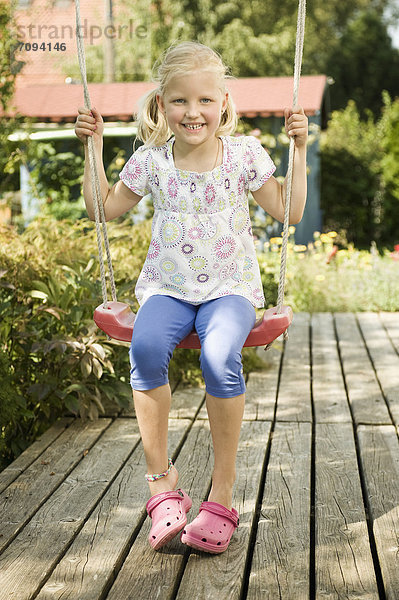 Girl swinging on swing  smiling  portrait