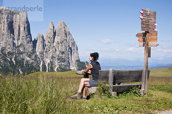 Italien  Mittlere erwachsene Frau sitzt auf der Bank und schaut zu Schlern in Südtirol.