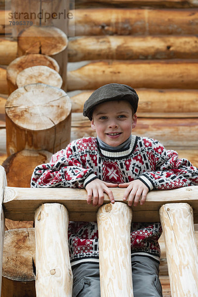 Junge steht auf dem Deck der Blockhütte  schaut auf die Kamera  Porträt