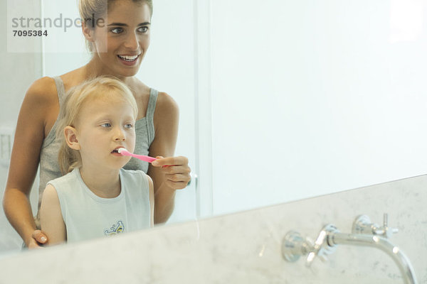 Mutter hilft Tochter beim Zähneputzen