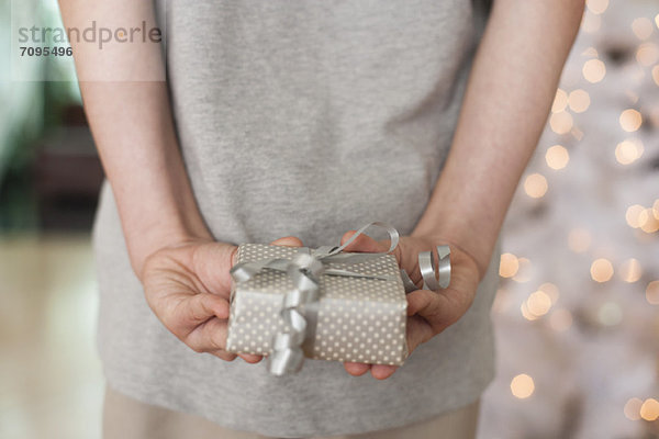 Mädchen hält Geschenk hinter dem Rücken