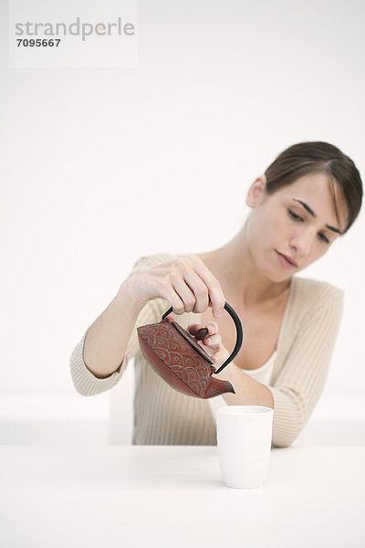 Frau schüttet eine Tasse Tee aus