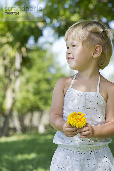 Kleines Mädchen mit Blume im Freien