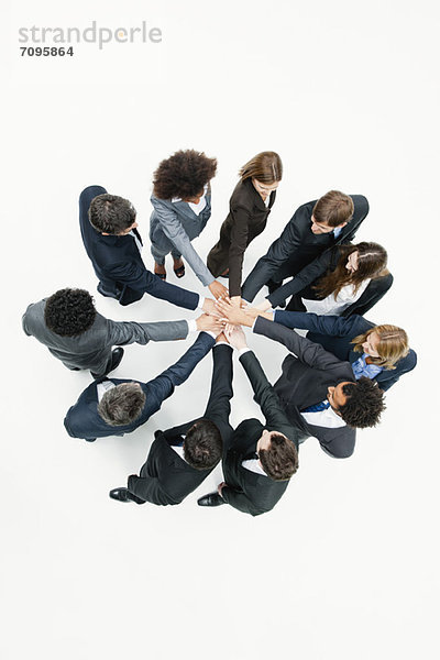 Geschäftsfreunde stehen im Kreis  die Hände in Motivationsübungen gefasst.