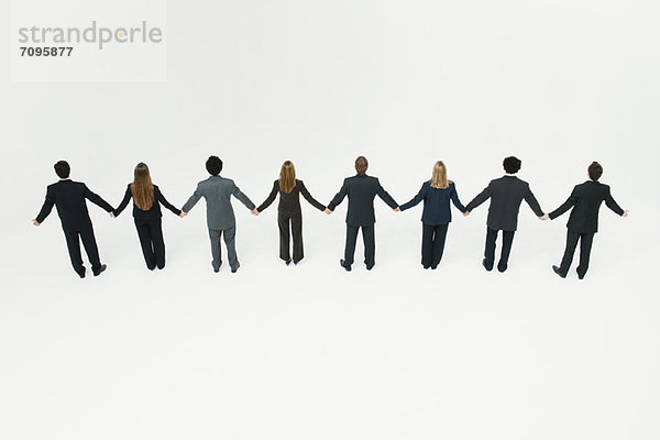Geschäftsmänner und Geschäftsfrauen stehen zusammen und halten Händchen.