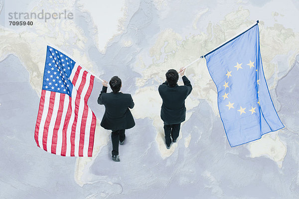 Geschäftsmann auf der Weltkarte mit amerikanischen und EU-Flaggen