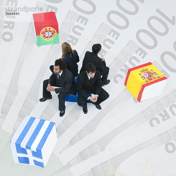 Vertreter Griechenlands  Portugals und Spaniens sitzen Rücken an Rücken auf der Flagge der Europäischen Union