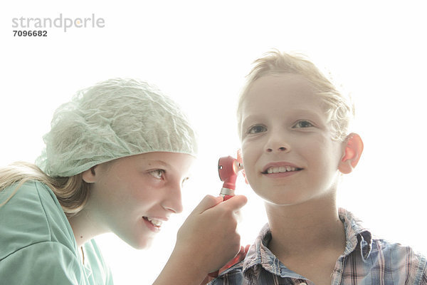 Mädchen und Junge spielen Arzt  das Mädchen untersucht das Ohr des Jungen