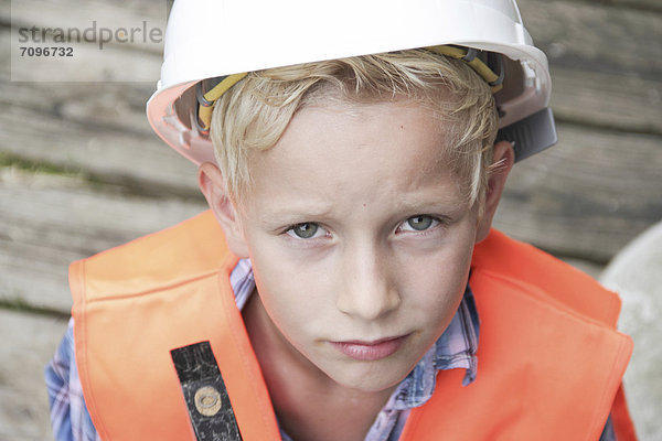 Junge als Bauarbeiter mit Bauhelm  Hammer und Warnweste