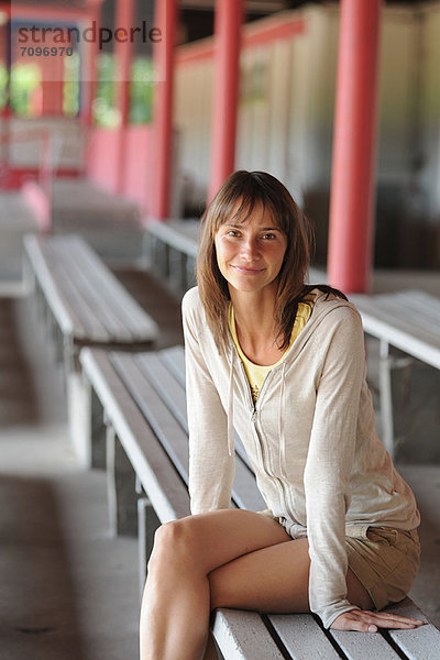 Lächelnde Frau auf der Bank sitzend