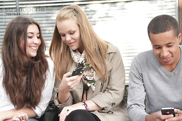 Jugendliche  die Mobiltelefone im Freien benutzen