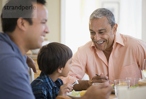 Hispanic grandfather  father and son eating dinner