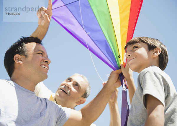 Hispanic grandfather  father and son flying kite