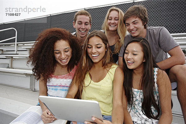 sitzend  Zusammenhalt  benutzen  Freundschaft  Schule  Tablet PC  unüberdachte Tribüne