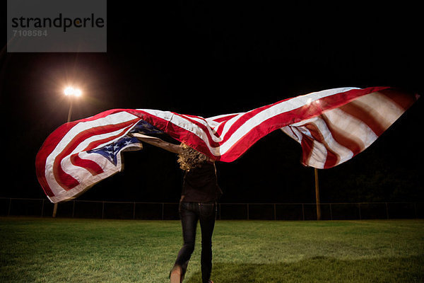 Mädchen mit amerikanischer Flagge bei Nacht