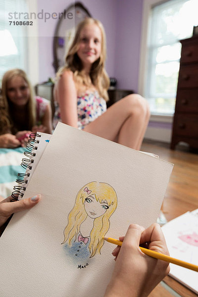 Girl Zeichnung Porträt eines Freundes auf dem Notebook