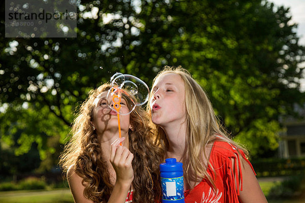 Zwei Mädchen beim Blasenblasen mit Blasenstab