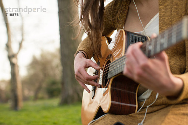 Junge Frau spielt Gitarre im Freien