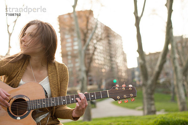 Junge Frau spielt Gitarre im Freien