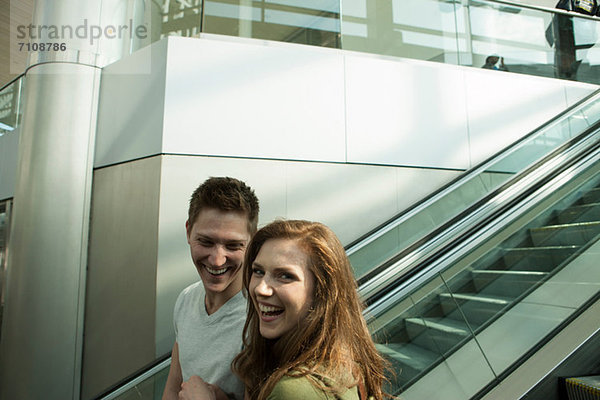 Junges Paar auf der Rolltreppe unterwegs