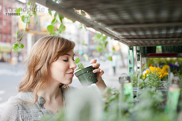 Junge Frau riecht eine Pflanze