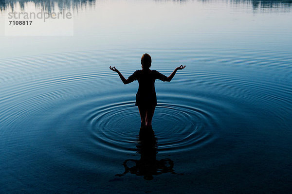 Frau meditiert im ruhigen See