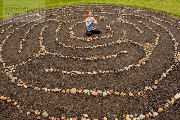 Frau meditiert im Steinlabyrinth
