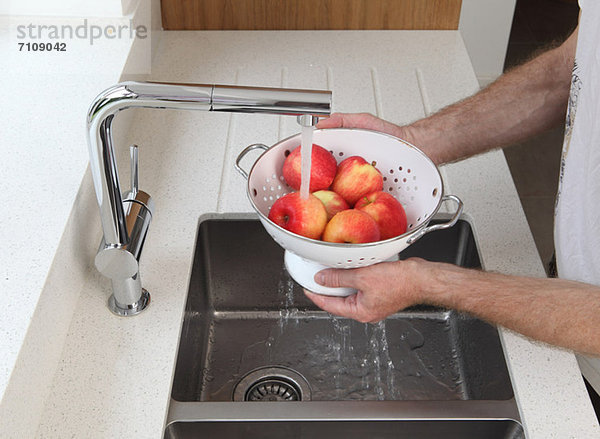 Mann wäscht Äpfel
