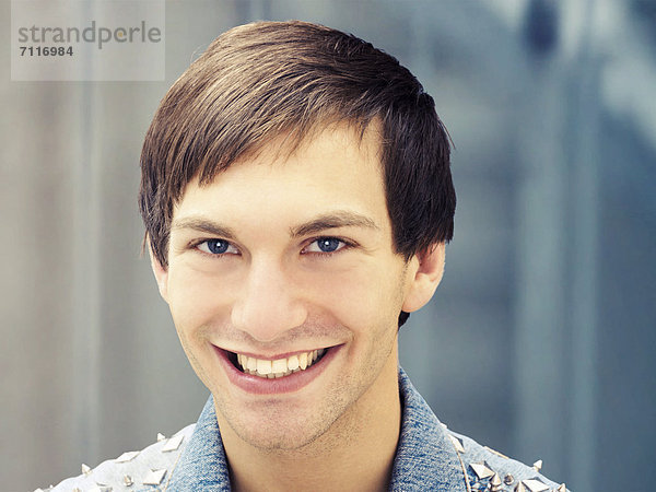 Lächelnder junger Mann mit nietenbesetzter Jeansjacke  Portrait