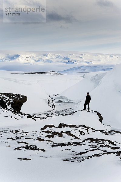 Mann am zugefrorenen und zugeschneiten Fluss  Winterlandschaft  Gletscher Vatnajökull  Hochland  Island  Europa