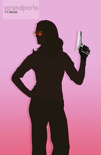 Silhouette einer Frau die eine Pistole hält