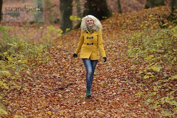 Fröhliche blonde junge Frau im Wald