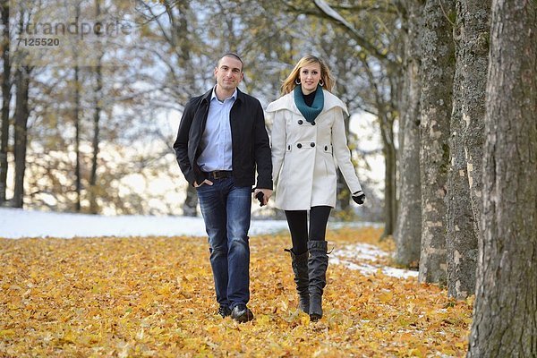Glückliches Paar geht in herbstlicher Umgebung spazieren