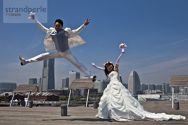 Skyline  Skylines  Frau  Mann  Fröhlichkeit  Hochzeit  Urlaub  Reise  Großstadt  springen  Asien  Japan  Yokohama