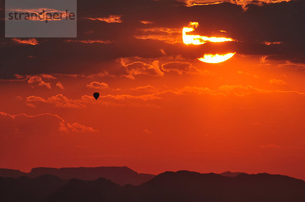 Farbaufnahme  Farbe  fliegen  fliegt  fliegend  Flug  Flüge  Berg  Wolke  Vitalität  Sonnenuntergang  Silhouette  Luftballon  Ballon  Sonnenaufgang  rot  Namibia  Namib  Afrika  Sossusvlei  Sonne
