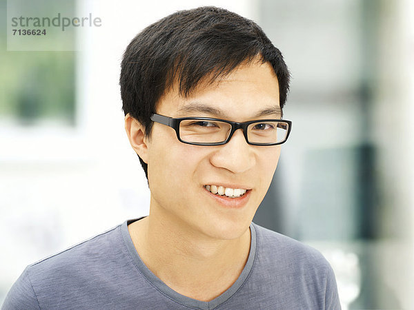 Junger Mann  Asiate  Student mit Brille  lächelnd
