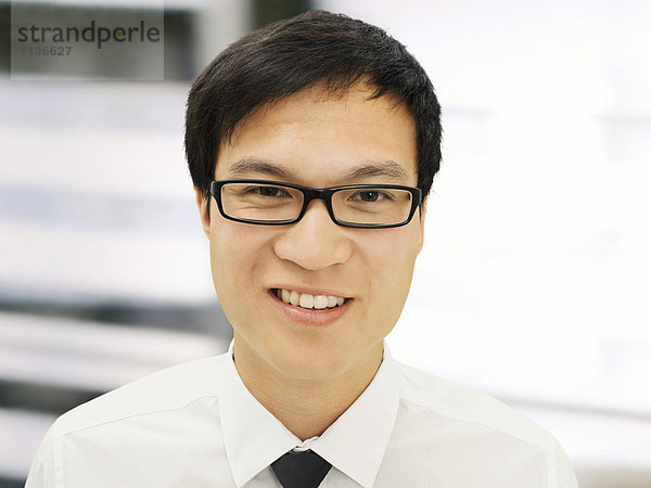 Junger Geschäftsmann  Asiate  mit Brille  lächelnd