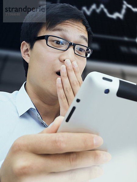 Geschäftsmann  Asiate  mit Brille  iPad  Börse  erstaunt  überrascht  aufgeregt